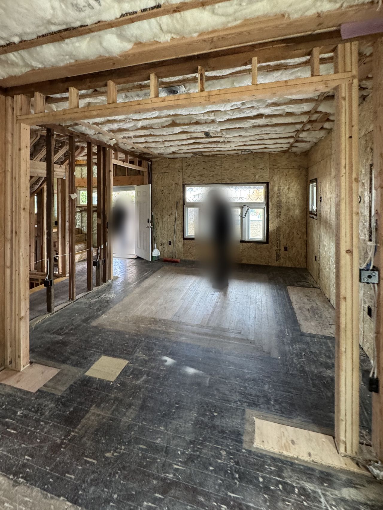 Living area of an older house open to the framing and insulation