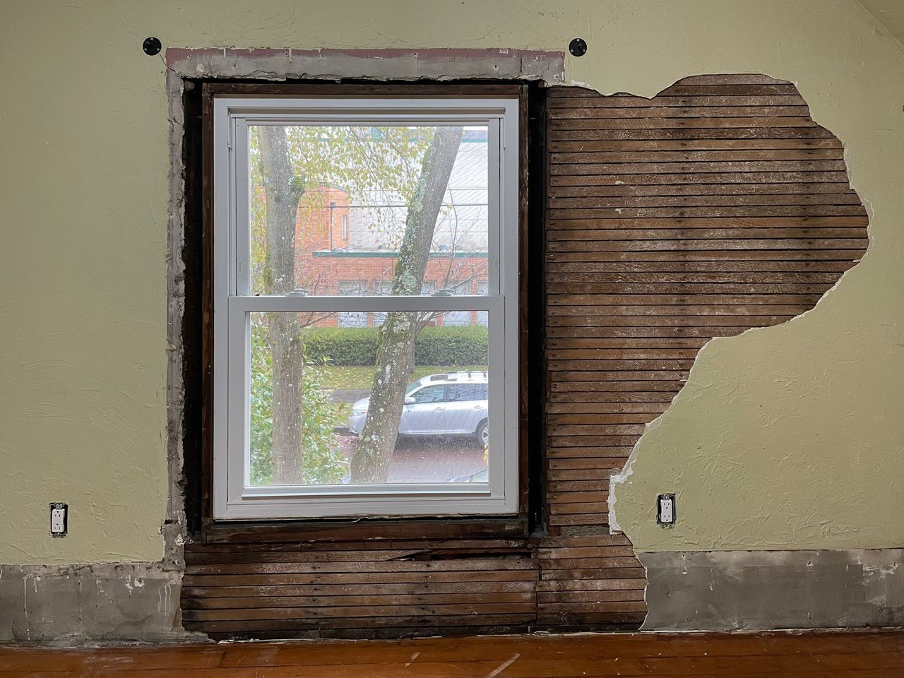 Plaster wall around a window broken out down to the wood lath