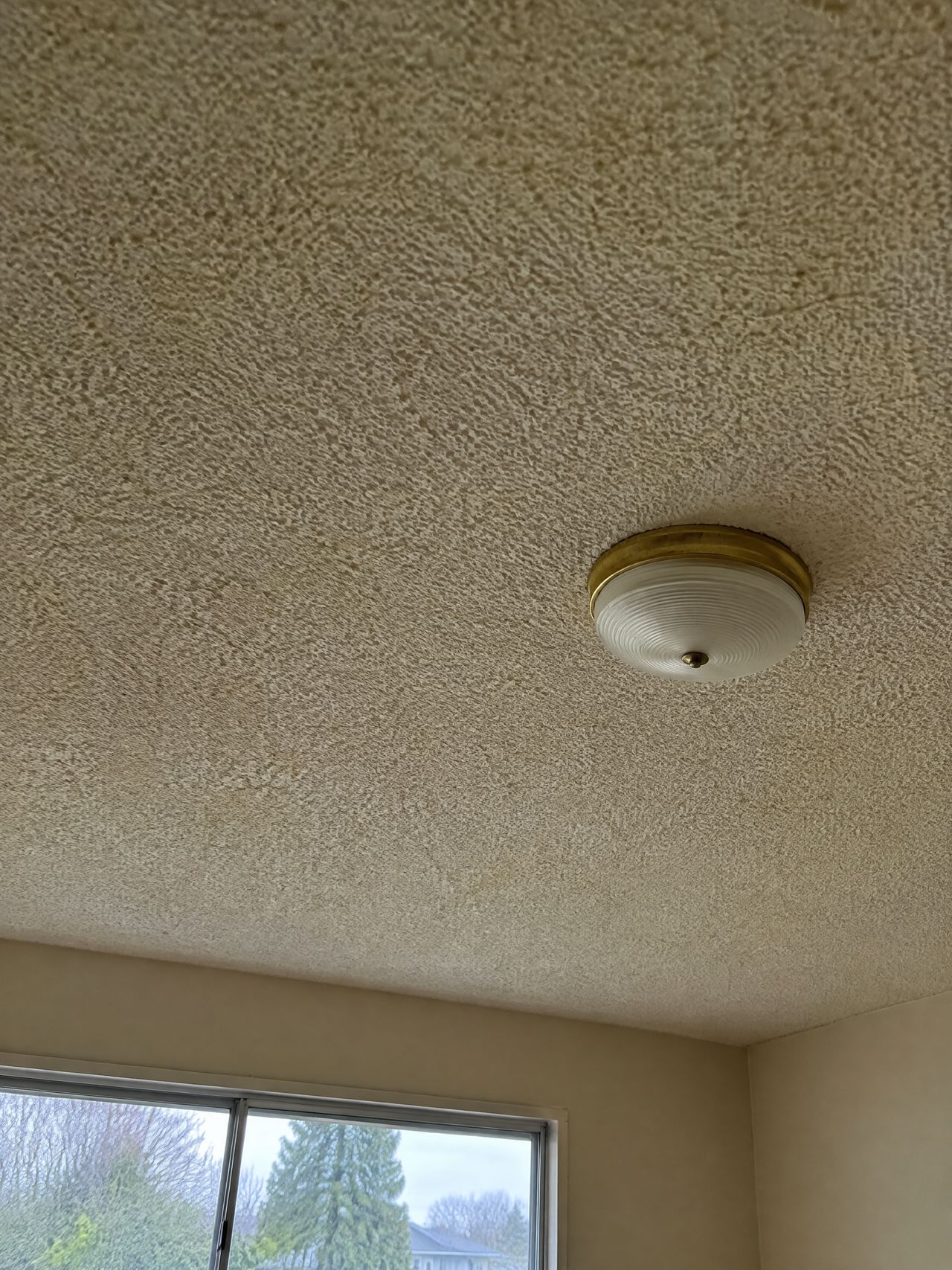 Living room ceiling covered in yellowed popcorn texture